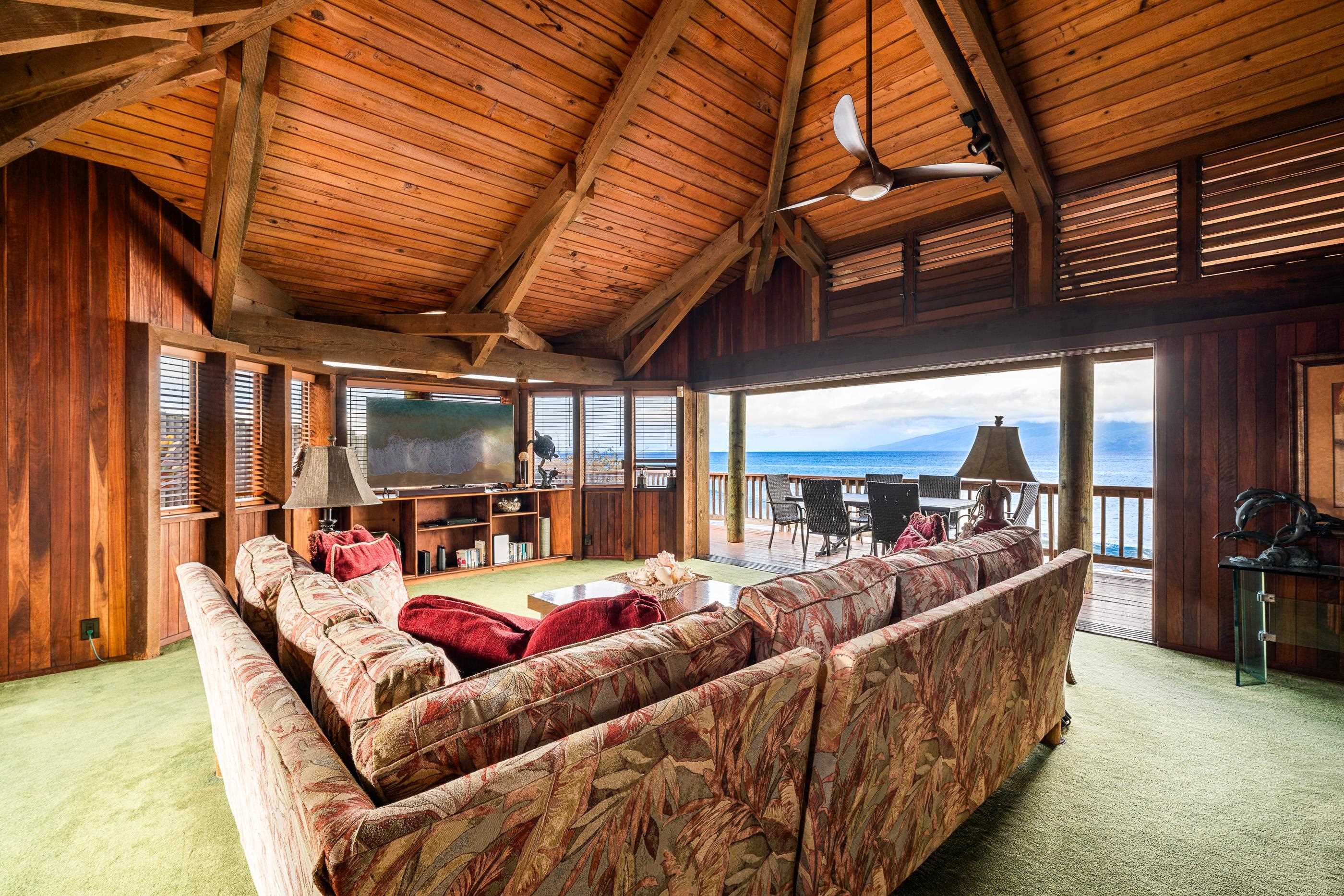 Sitting area under high beams, sliding doors opened to the wraparound deck