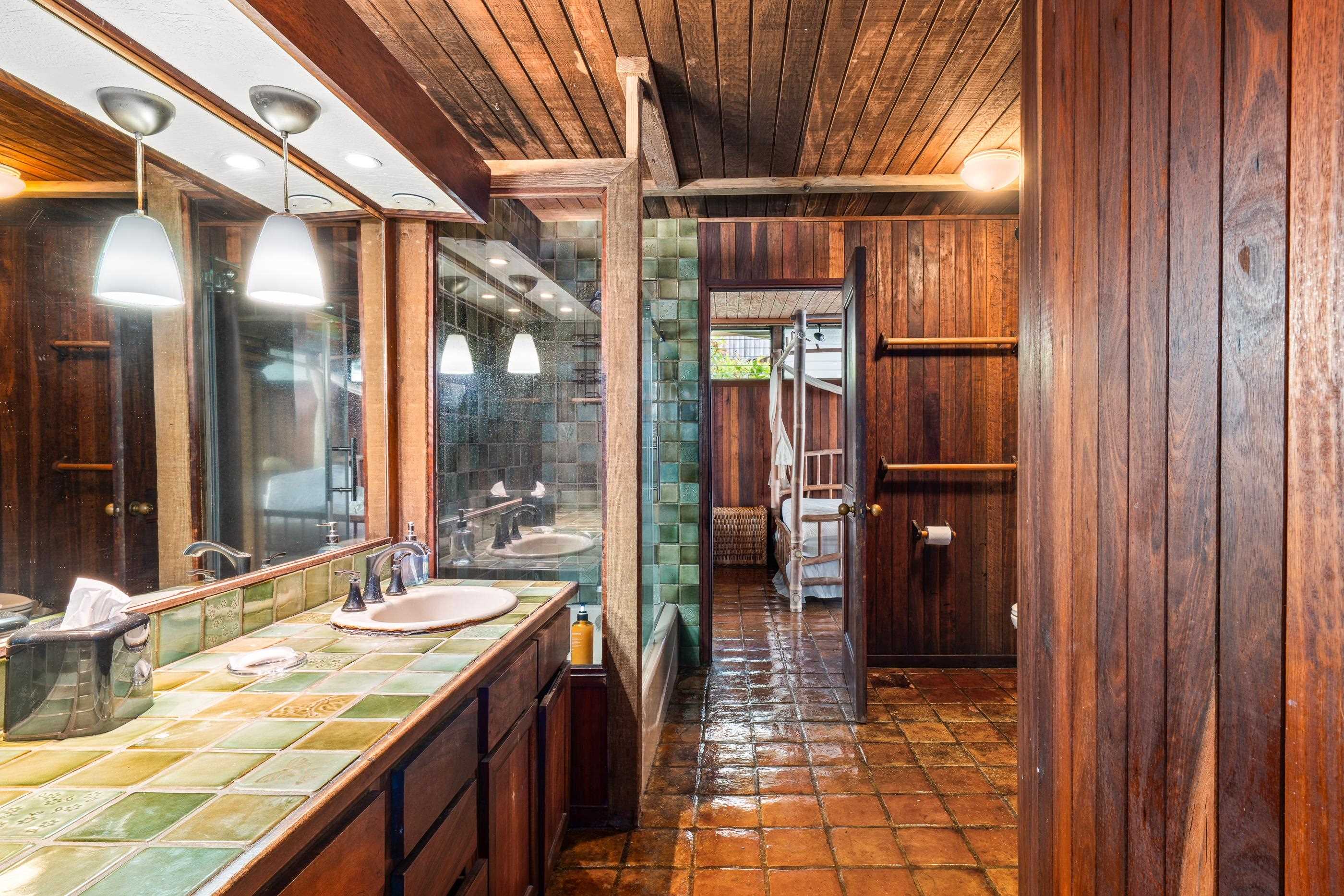 Green-tiled double vanity with a view through to the dressing area